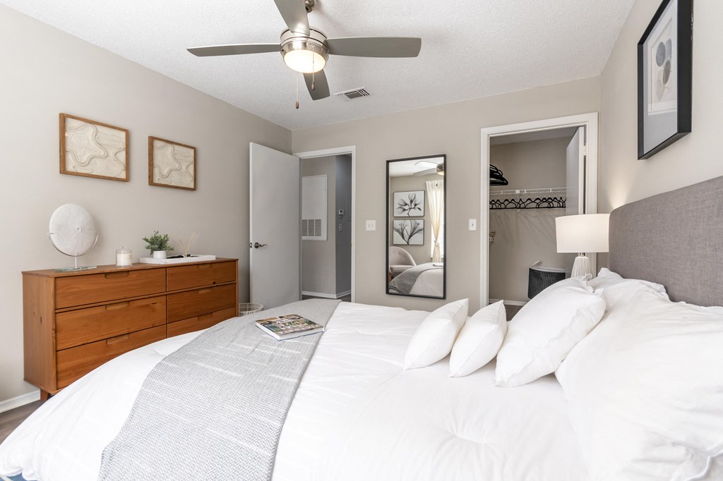 A bedroom with a large bed, a ceiling fan, and a dresser.