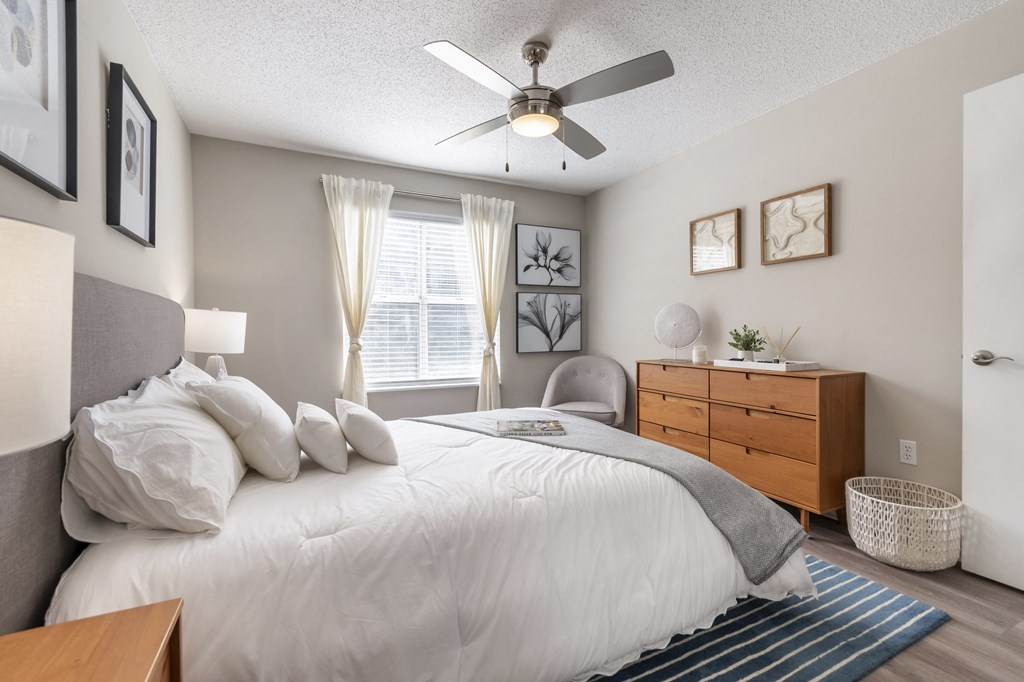 A bedroom with a bed, nightstand, and a ceiling fan.