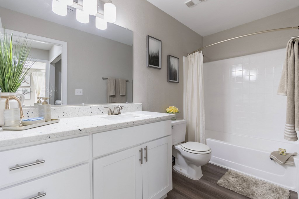 A white bathroom with a toilet, sink, and mirror.