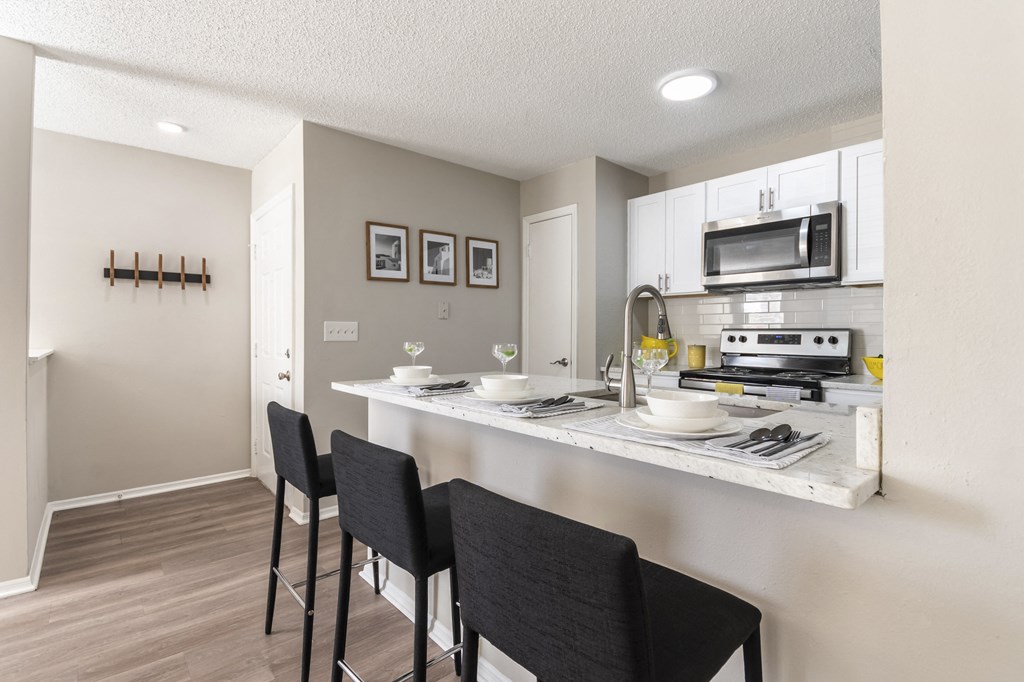 A kitchen with a white counter and black chairs.