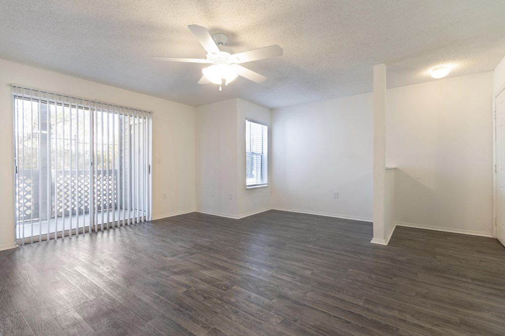 A room with a ceiling fan and a window with blinds.