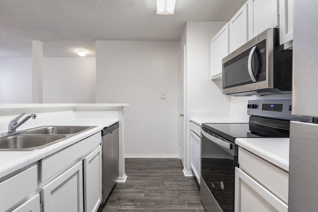 A kitchen with white cabinets and black countertops.