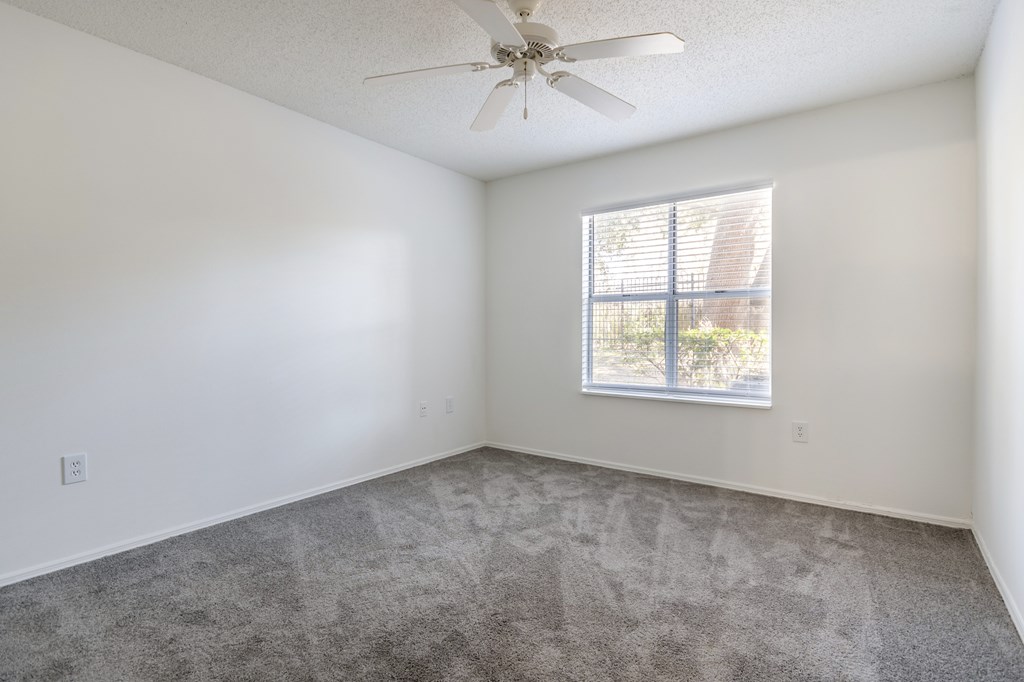 A room with a ceiling fan and a window with blinds.