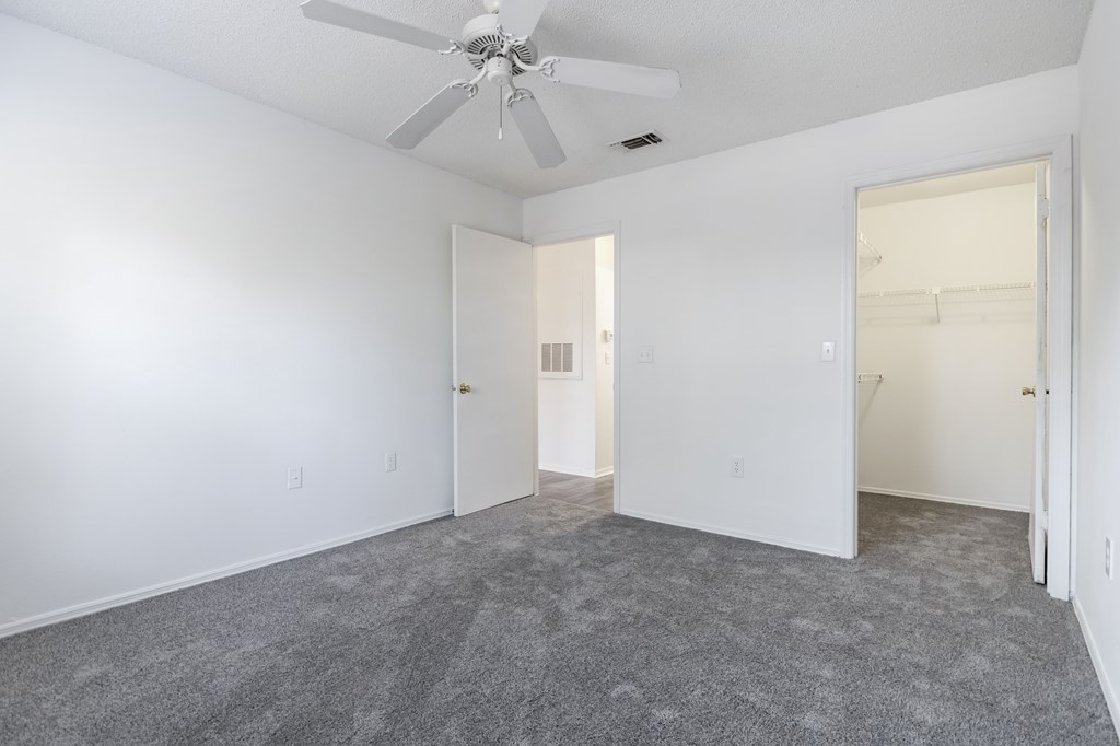 A room with a ceiling fan and carpeted floor.