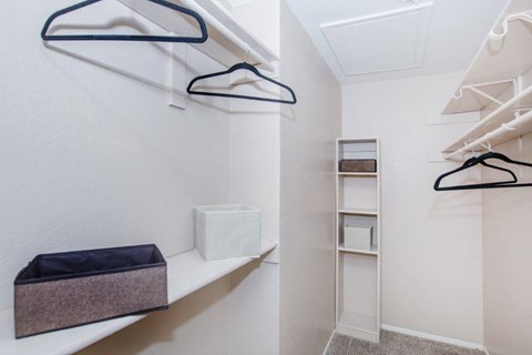 A white closet with a shelf and a purple storage bin.