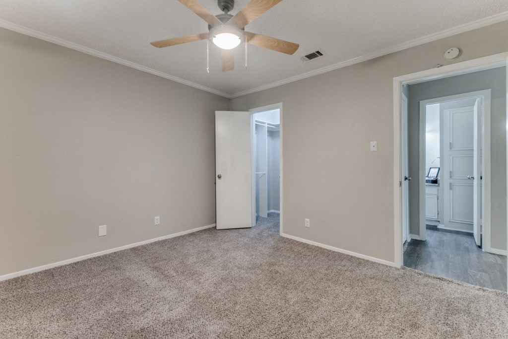 a bedroom with a ceiling fan and a door to a bathroom
