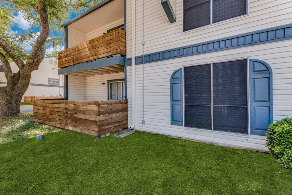 a backyard with green grass and a white house with a blue door