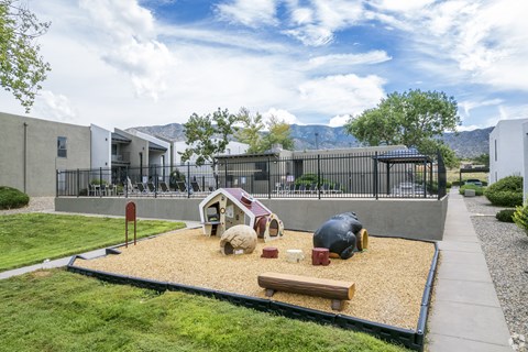 A playground with a sandbox and a bench.