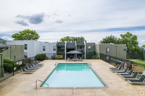 A swimming pool surrounded by lounge chairs and umbrellas.
