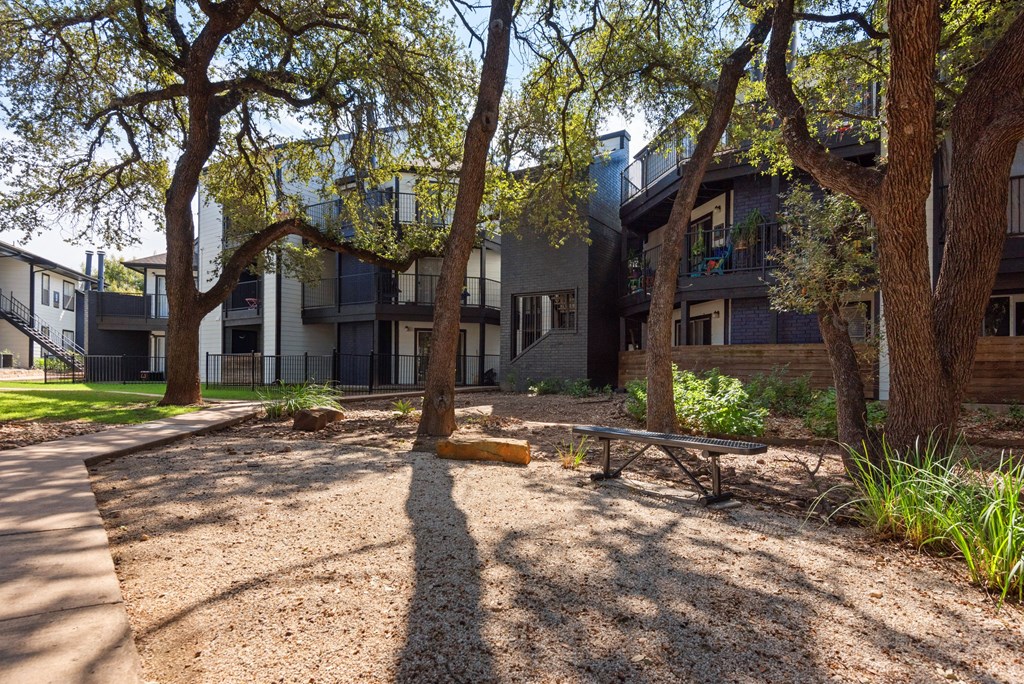 a park with trees and a bench in front of a building