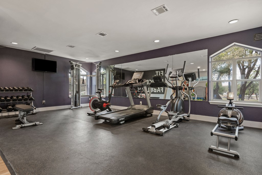 a home gym with a purple accent wall and a large window