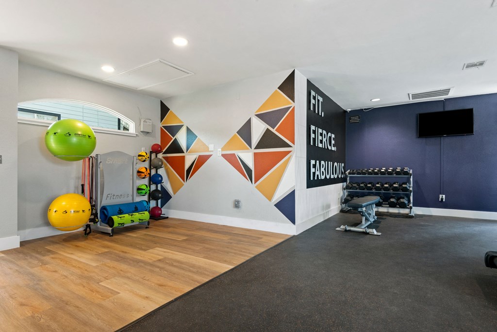 a workout room with a large green ball on the floor and a colorful geometric mural on the