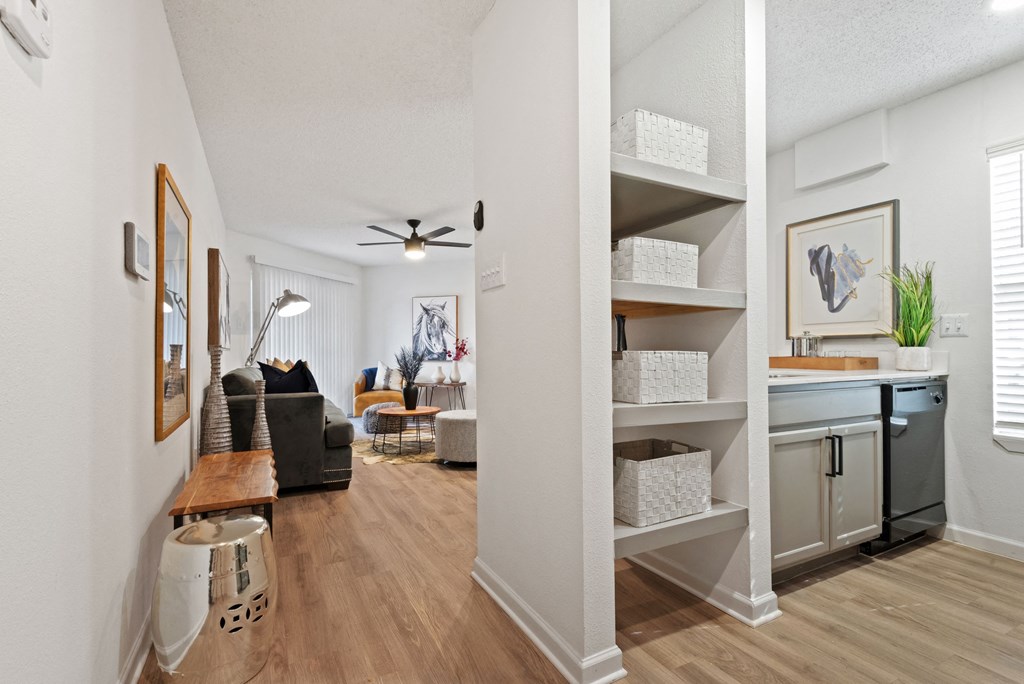 a living room and kitchen area with white walls and hardwood flooring