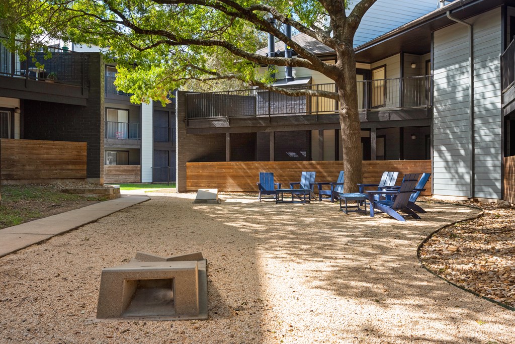 a fire pit and chairs in the courtyard of a building