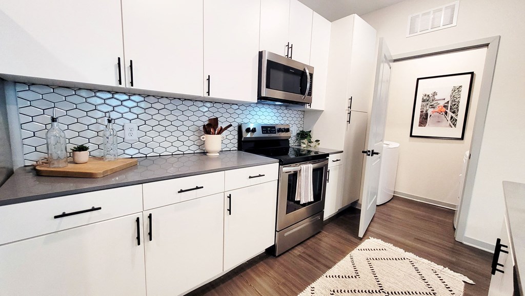 a kitchen with white cabinets and a black and white rug