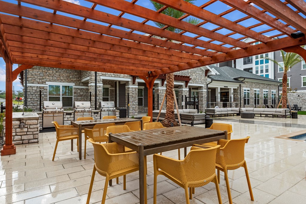an outdoor patio with a pergola and tables and chairs