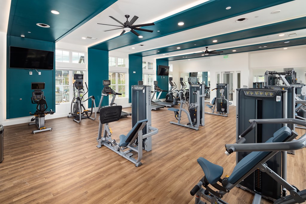 A gym with a variety of equipment including treadmills, weights, and exercise machines.