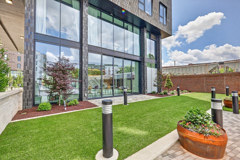 A modern house with a large glass window and a green lawn in front.