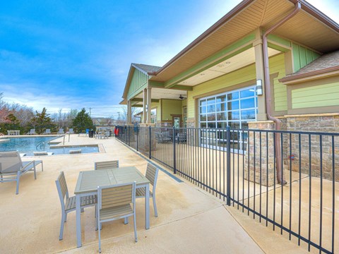 a patio with tables and chairs next to a swimming pool