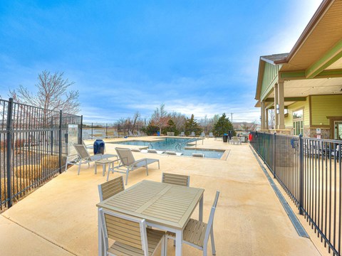 a patio with tables and chairs next to a pool