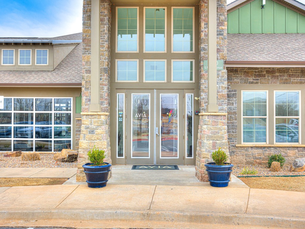 the front door of a house with two potted plants on the sidewalk
