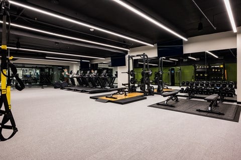A well-lit gym with various exercise equipment.