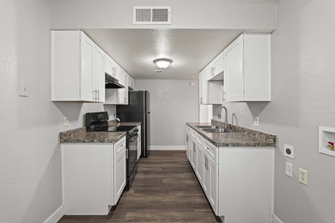 A kitchen with white cabinets and a granite countertop.