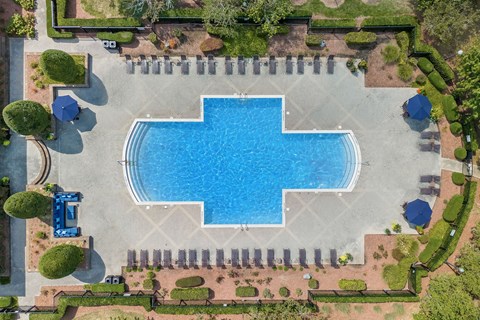 A large blue swimming pool surrounded by a brick patio and a grassy area.