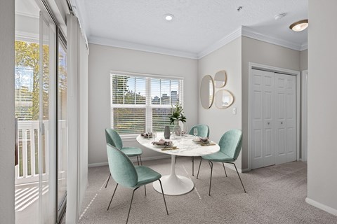 A dining room with a white table and green chairs.