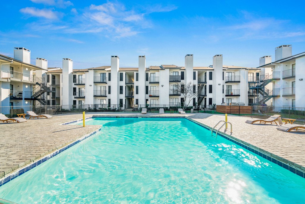 a swimming pool with an apartment building in the background