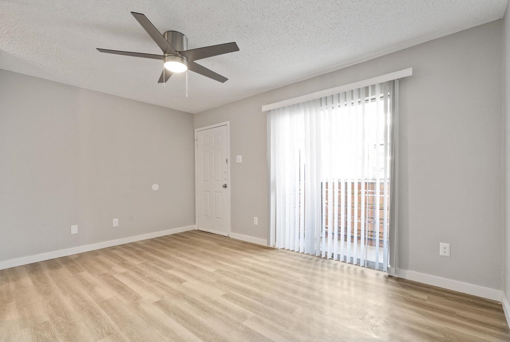 the spacious living room with a large window and a ceiling fan