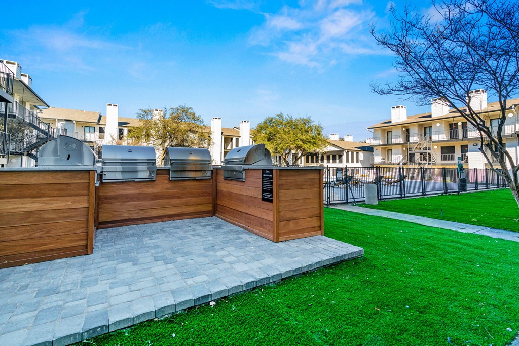 the backyard has a grill and a patio with green grass