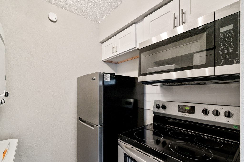 a kitchen with a stove refrigerator and microwave