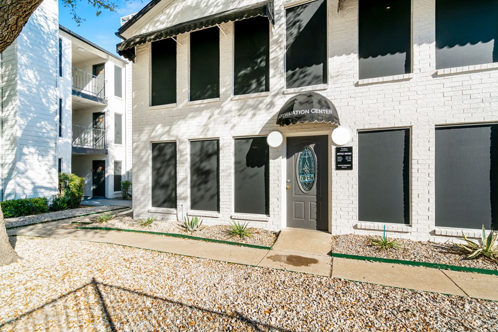 a white building with a blue door and a sidewalk in front of it