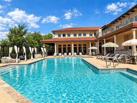 A large swimming pool in front of a building with a balcony.