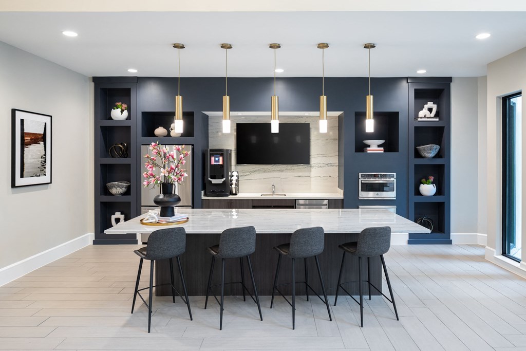 a kitchen with a large island with four chairs and a tv