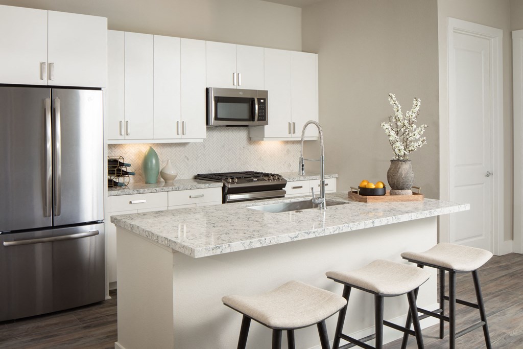 a kitchen with a marble counter top and a stainless steel refrigerator