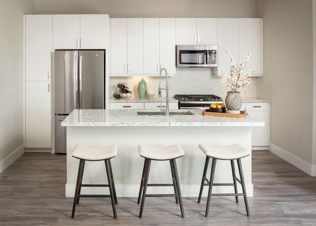 a kitchen with a marble counter top and three stools