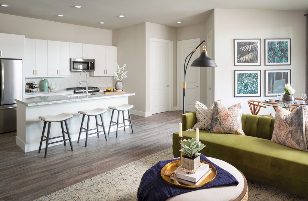 a living room with a kitchen and a green couch