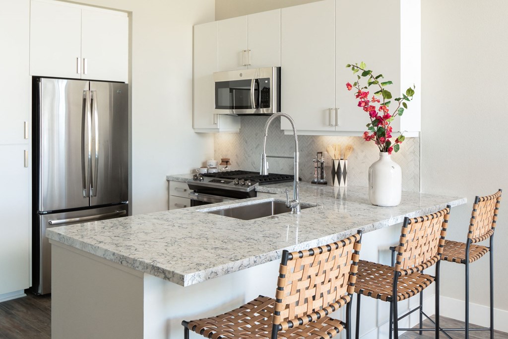 a kitchen with a marble counter top and a stainless steel refrigerator
