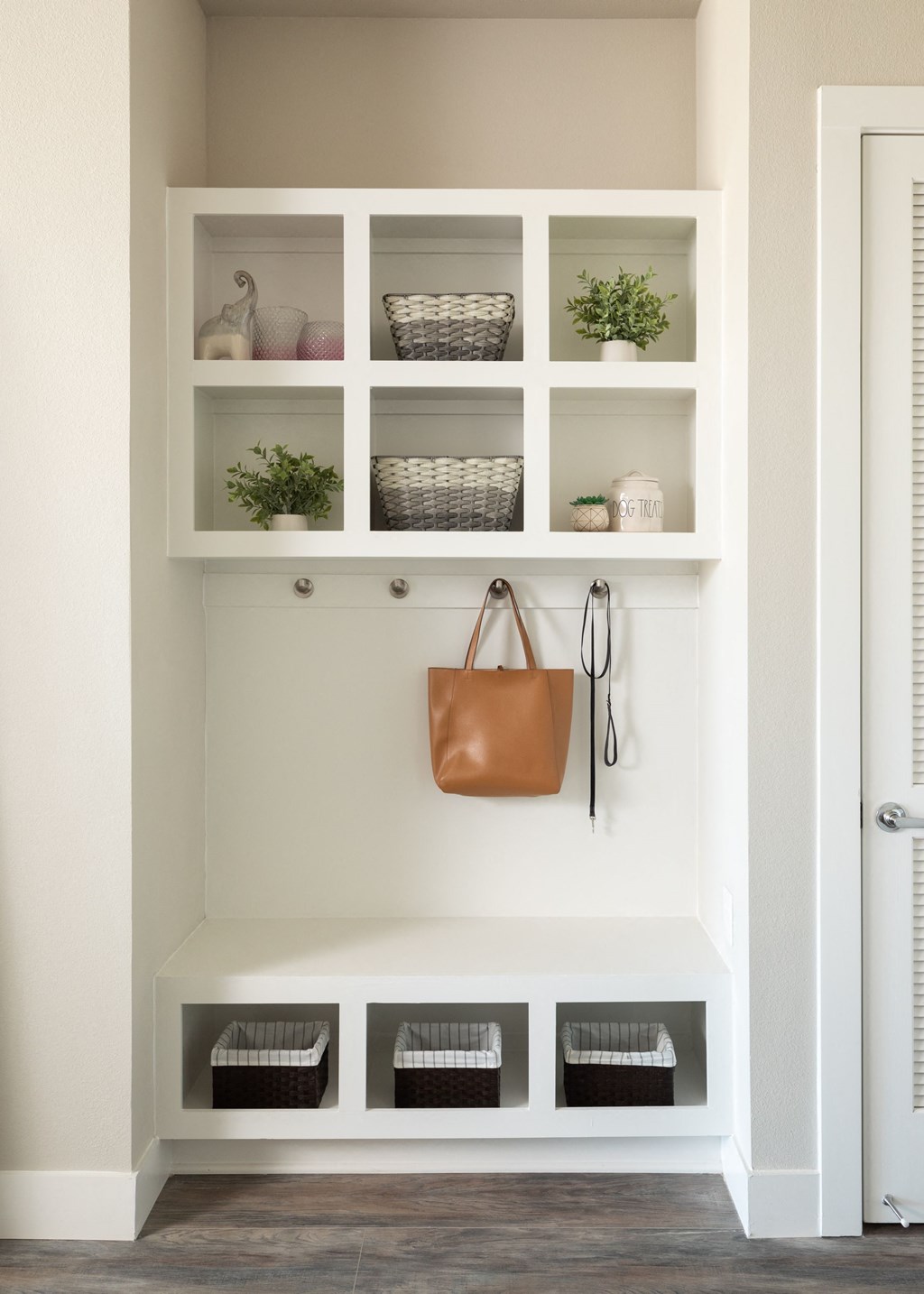a living room with white shelves and a bag hanging on a wall
