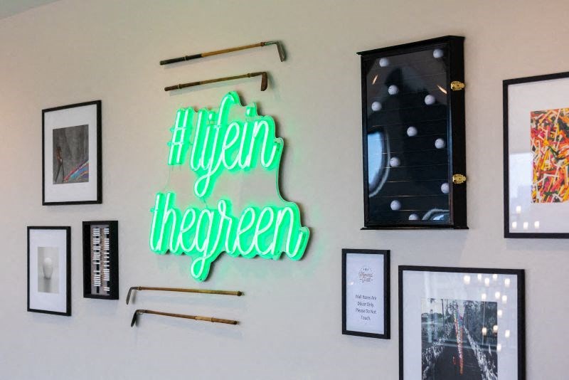 a neon sign on a wall next to pictures and artwork