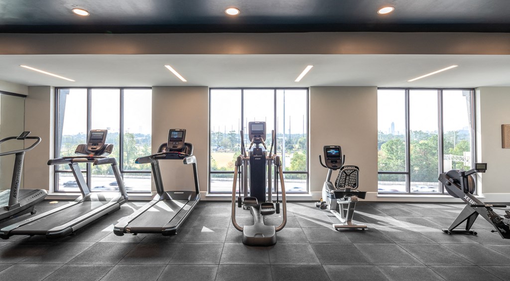 a gym with cardio machines and a view of the city
