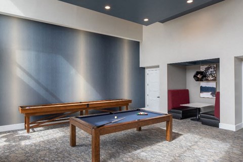 A pool table in a room with a bench and a picture on the wall.