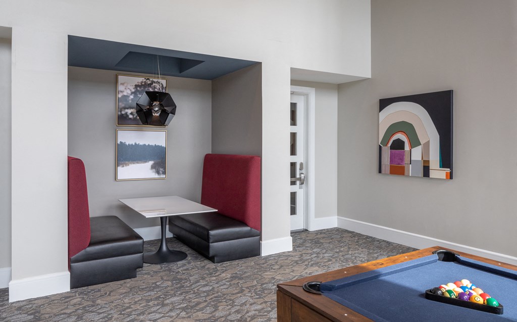 a room with a pool table and chairs and a table with a painting and a