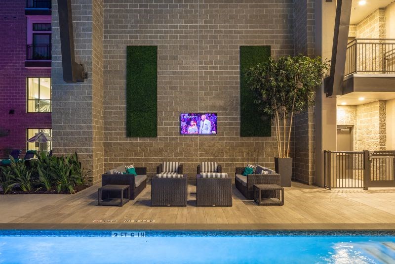 a swimming pool with chairs and a tv on a brick wall
