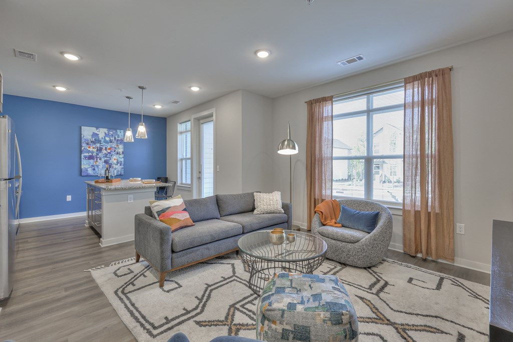 A living room with a grey couch and a patterned ottoman.