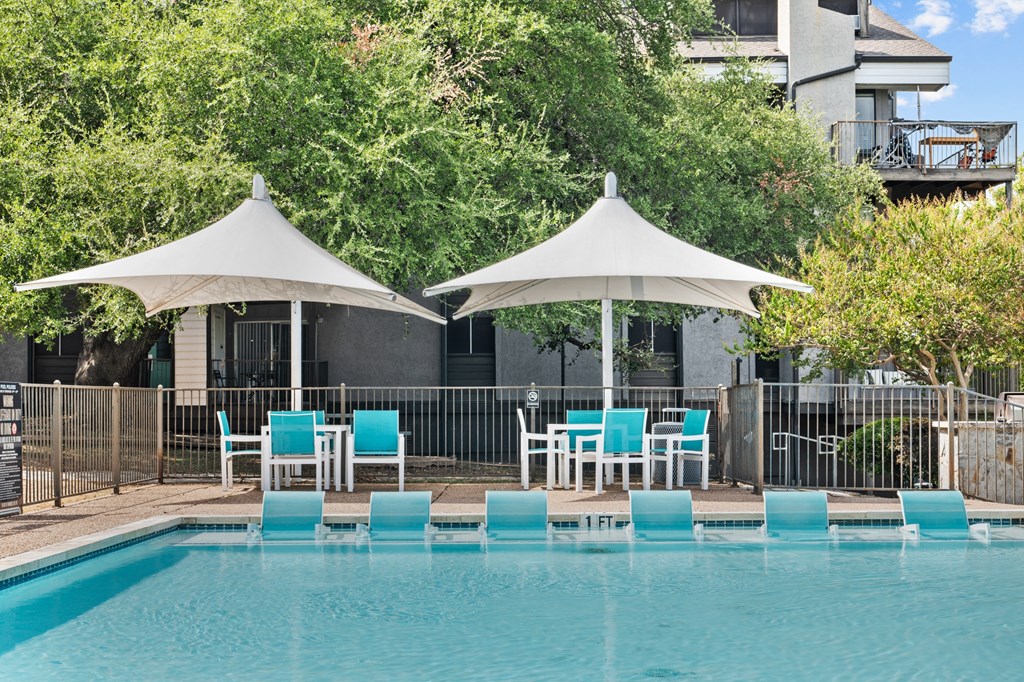 a swimming pool with blue chairs and umbrellas next to a resort pool
