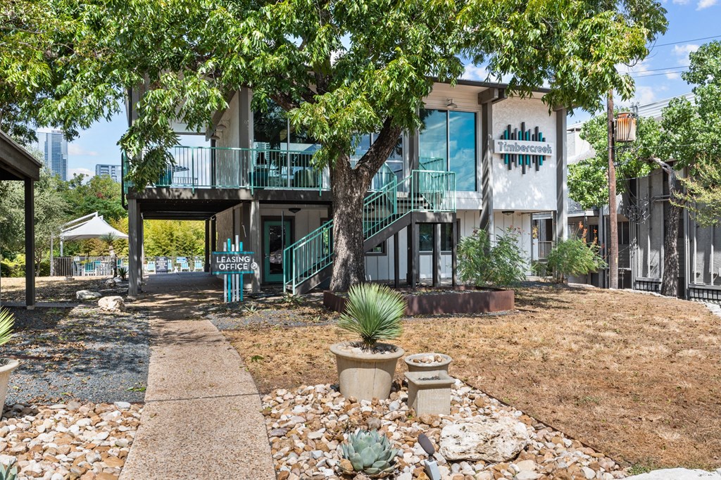 a house with a sidewalk and trees in front of it