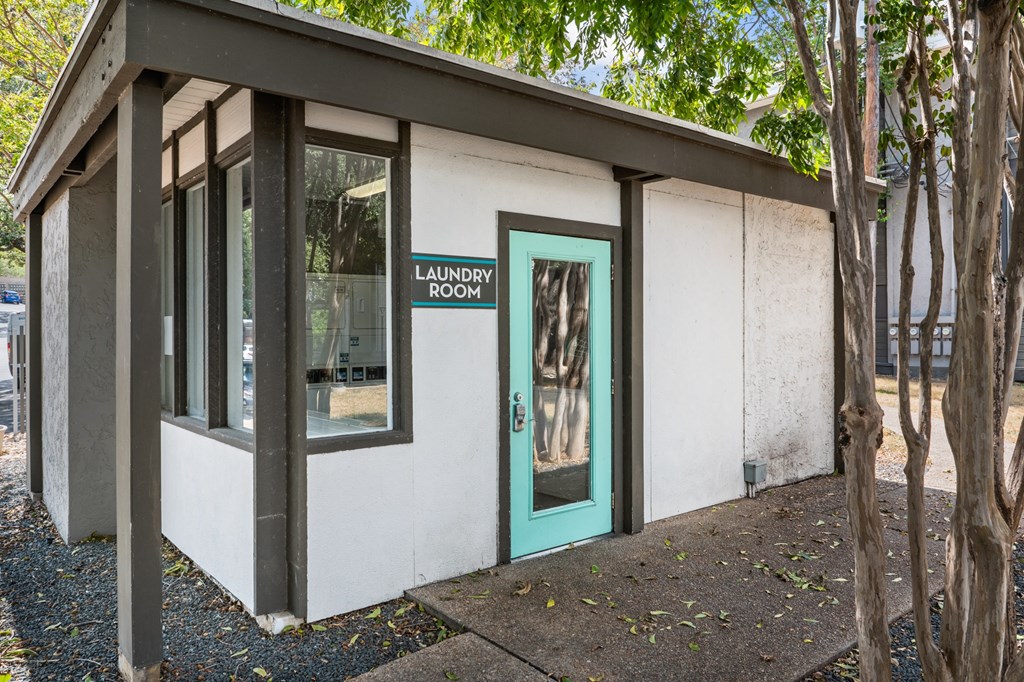 a white building with a green door and a sign that reads laundry room
